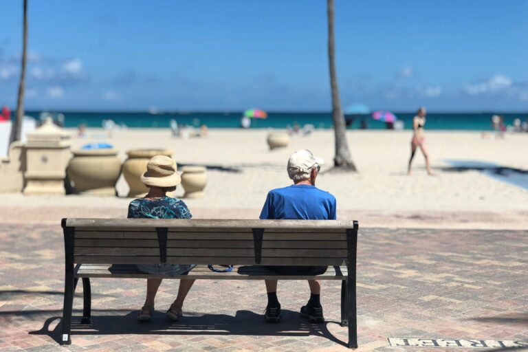 Retired couple on bench overlooking beach