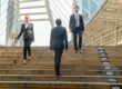 Three office workers crossing on some steps.