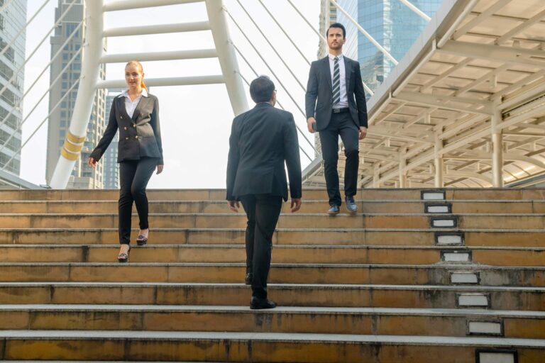 Three office workers crossing on some steps.