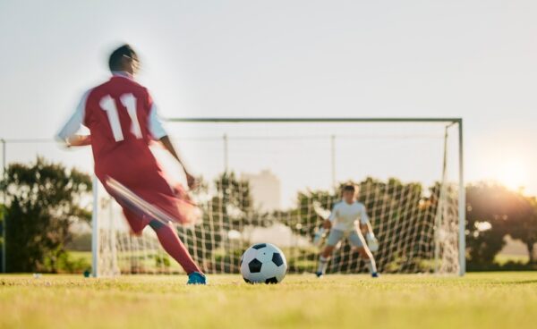 Soccer,,Goal,Post,And,Ball,,Soccer,Player,Running,And,Kicking A footballer taking a shot at a goal.