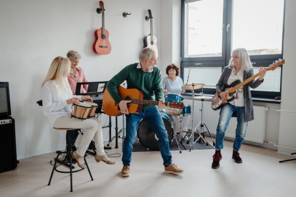 Group,Of,Seniors,Meeting,To,Play,Musical,Instruments,Together,In A group of people in their 50s playing musical instruments in a band.