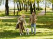 A couple and a dog walking in a park.