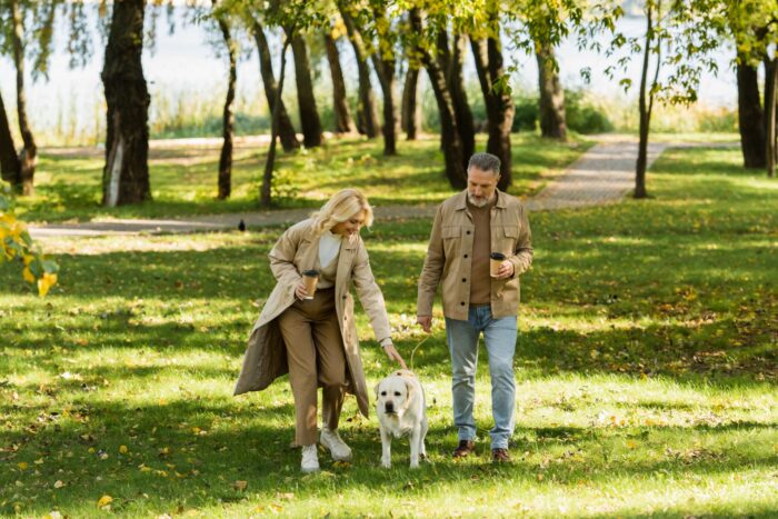 A couple and a dog walking in a park.