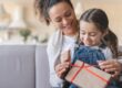 A mother and daughter unwrapping a gift.