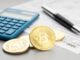 A representation of cryptocurrency next to a calculator.