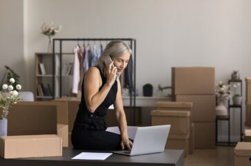 Female boss taking notes on a laptop as she discusses with someone on the phone